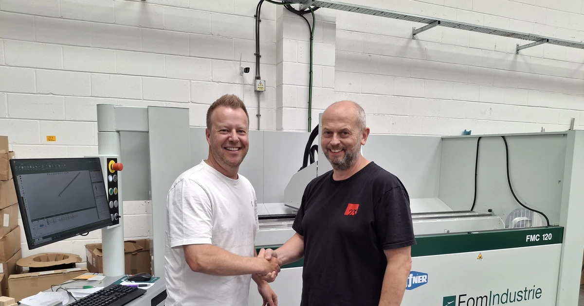 Two men shaking hands beside a FOM Industrie FMC 120 CNC machining centre in an industrial workshop