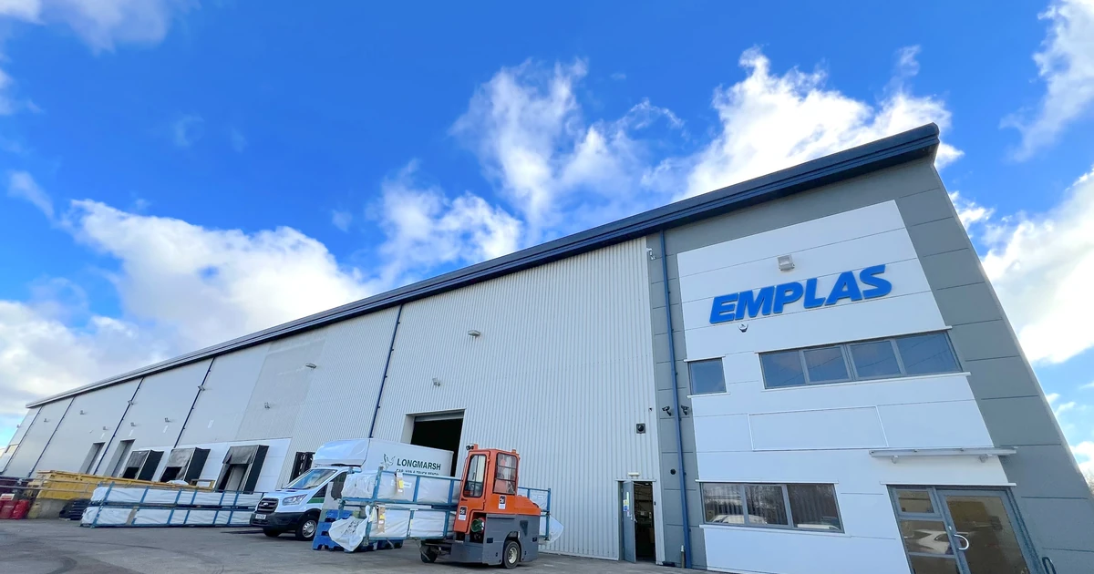 Exterior view of the new Emplas manufacturing facility under blue sky with company logo on the building