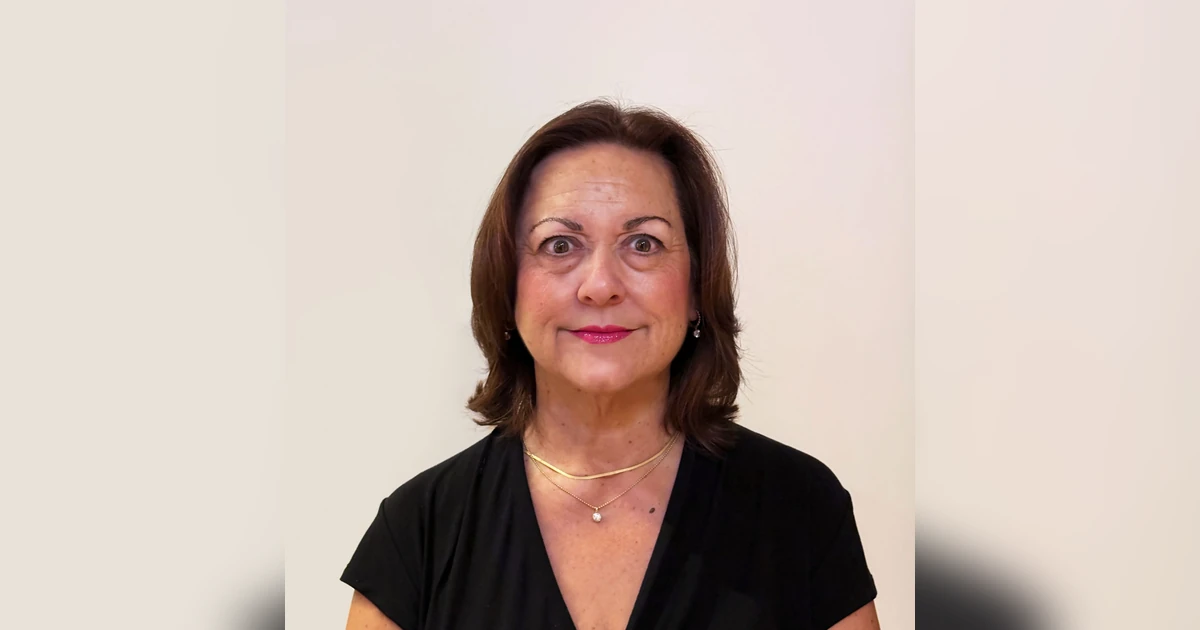 Portrait of a woman with brown hair wearing a black top against a plain background