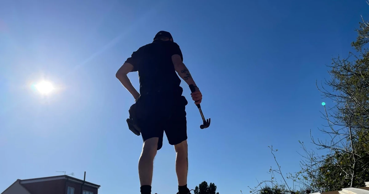 Man working on a rooftop under a blue sky holding a hammer, representing Richard Hopcroft from Southside Maintenance Limited
