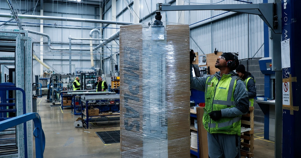 Workers in Emplas factory handling wrapped fire doors on a production line