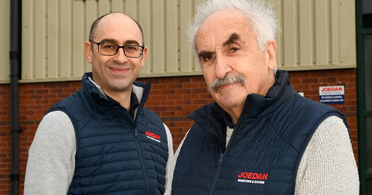 Two men in Joedan branded vests standing in front of Joedan Windows &amp; Doors Tewkesbury Design Centre sign