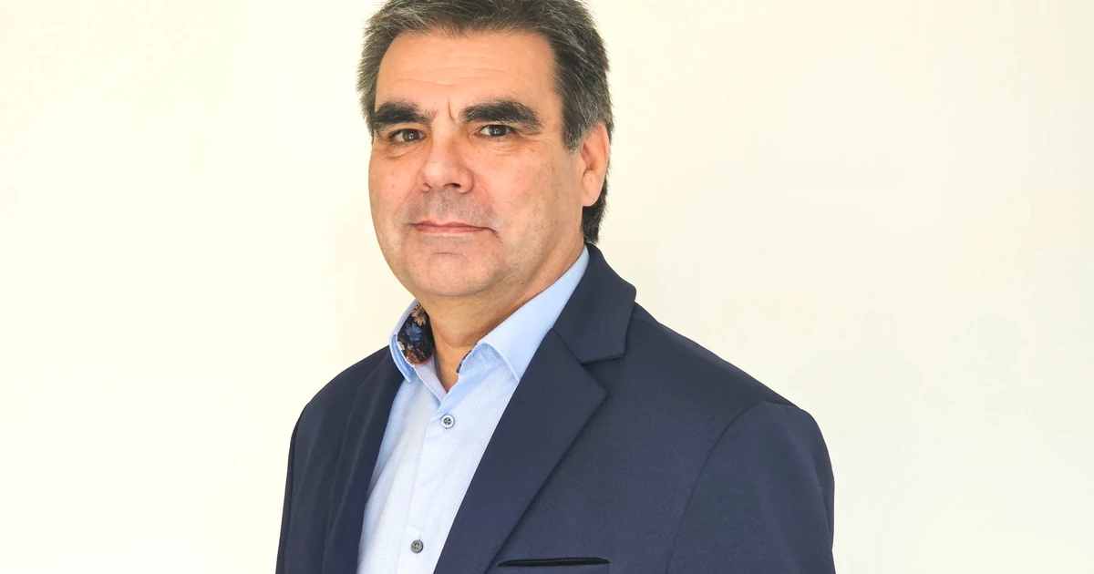 Portrait of Richard Sellman dressed in a blue blazer and light blue shirt against a plain light background