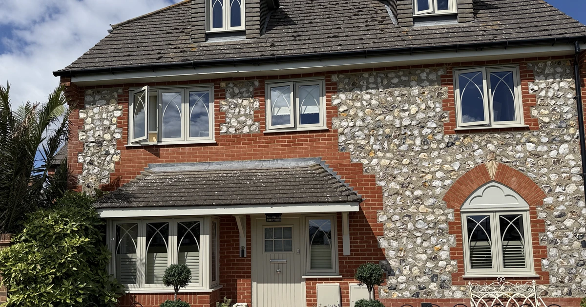 Period property with gothic-style windows installed by Jadeite Glazing featuring flint and red brick facade