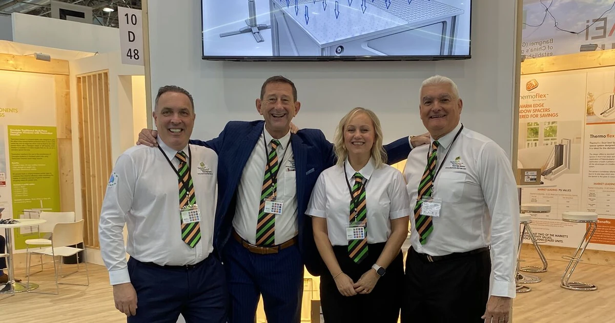 Four Thermoseal team members posing at their trade fair stand with product displays and a screen in the background