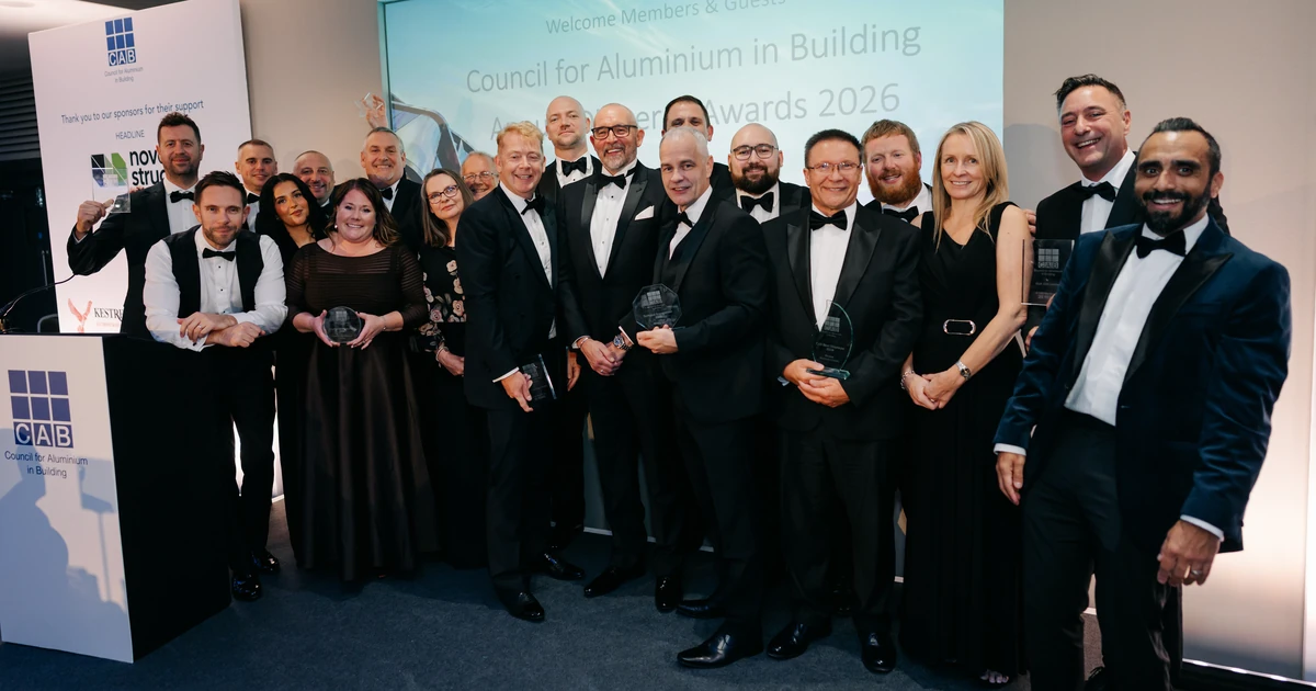 Group of formally dressed attendees holding awards in front of a CAB Gala Dinner presentation screen