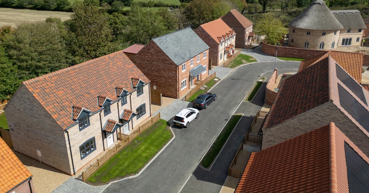 Aerial view of newly constructed traditional styled houses at Church Farm housing development amidst green landscape and blue sky