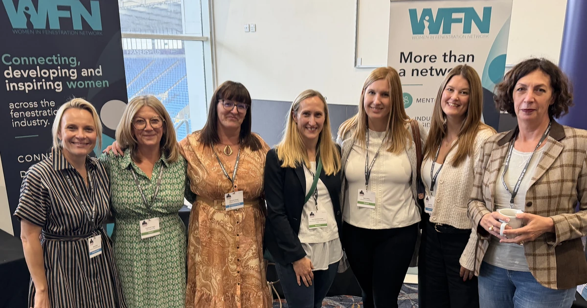 Seven women standing together at a WFN event with WFN banners in the background