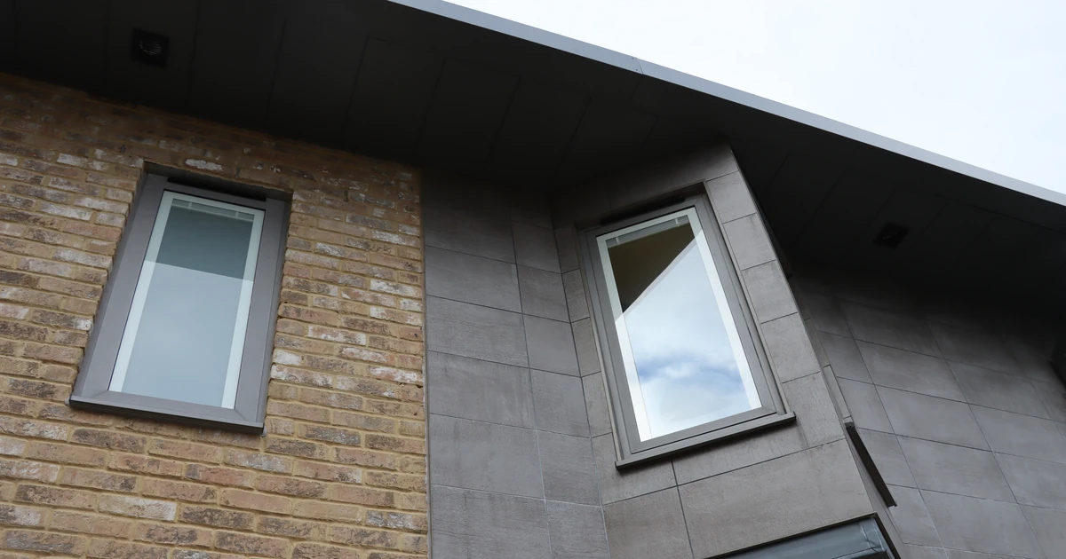 Modern building exterior with close-up of two installed windows with different frame styles